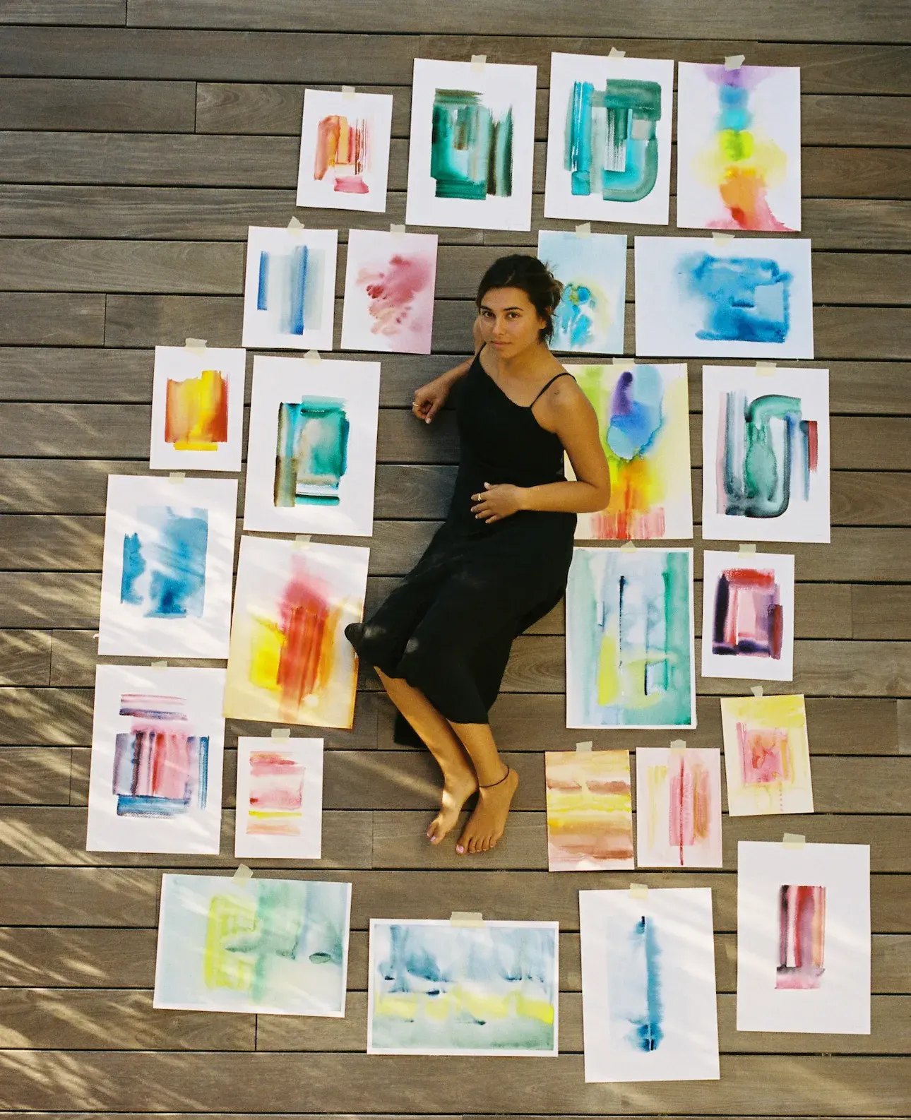 Ari lying among her watercolor paintings
