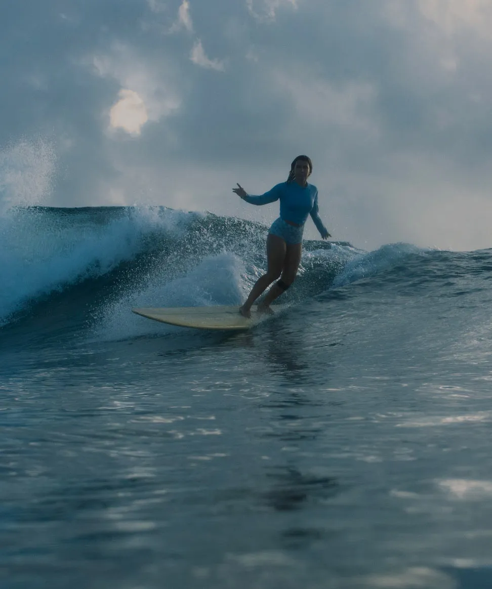 Ari surfing a wave under a stormy sky